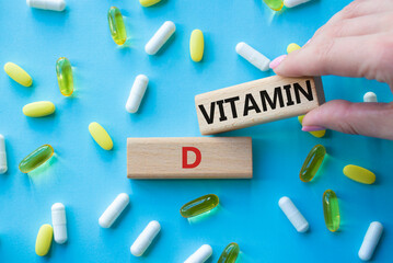 Vitamin D symbol. Concept word Vitamin D on wooden blocks. Beautiful blue background with pills. Doctor hand. Medicine and Vitamin D concept. Copy space