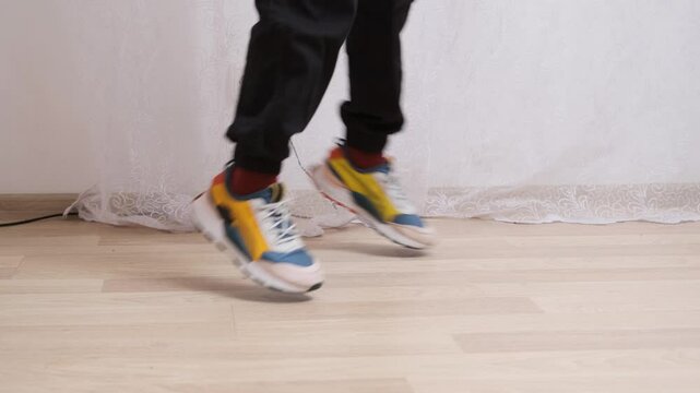 Dancer in sneakers practices shuffle dance steps in slow motion, showcasing skillful footwork and rhythmic movement