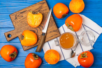 Persimmon jam with slices of ripe persimmon on wooden textured table. Delicious persimmon jam. Marmalade. Healthy sweets. Vegan. Close-up. Space for text. Copy space.
