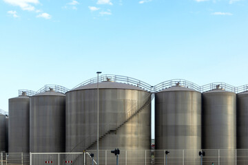 Row of Industrial Silos or Tanks Under a Clear Sky.