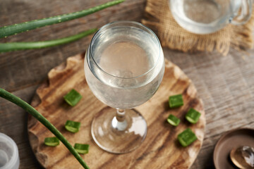 A glass of natural aloe vera juice with fresh leaf on a table