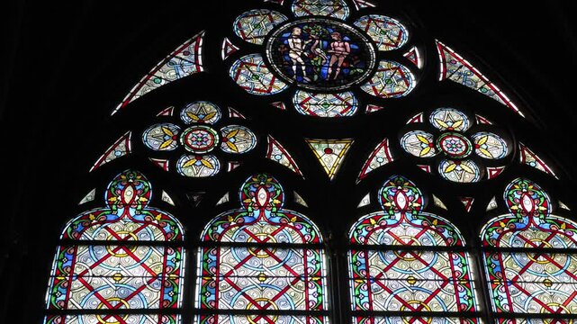Stunning stained glass window illuminating Notre Dame Cathedral in Paris with vibrant hues and detailed patterns