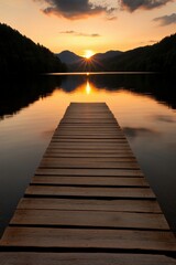 Obraz premium Sunset over calm lake with wooden dock reflecting golden light