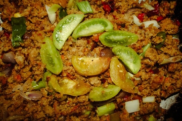 The savory and slightly spicy oncom is served with fresh green tomato slices arranged in a circle on top.