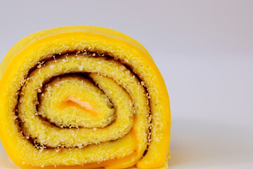 Fototapeta premium Yellow cake with swirl on top. Roll of yellow and gray on gray background. A roll of gray lies on a yellow background of jam sweetness. A roll of sweet jam lies on a gray lifestyle background.