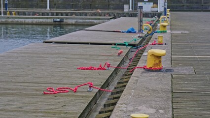 Obraz premium Marine Floating Bridge Platform Moored with Polypropylene Nylon Plastic Rope Around Yellow Metal Bollard Mounted at Harbor Concrete Pier 