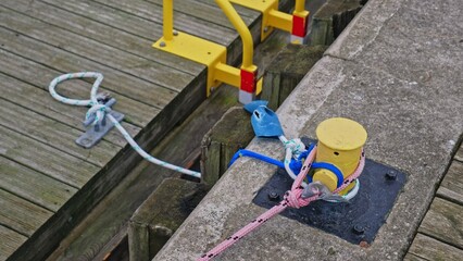 Transport Barge Moored with Polypropylene Nylon Plastic Rope Around Yellow Metal Bollard Mounted at Harbor Concrete Wharf