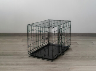 A black empty cage for pets sits on the floor of a cozy living room