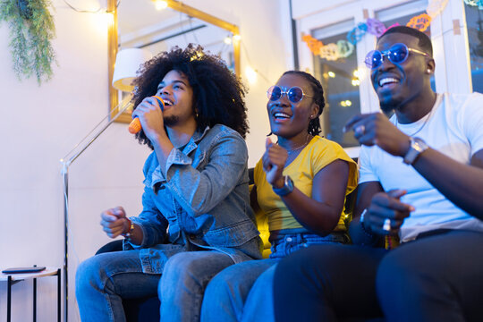 Friends singing karaoke at home party - Powered by Adobe