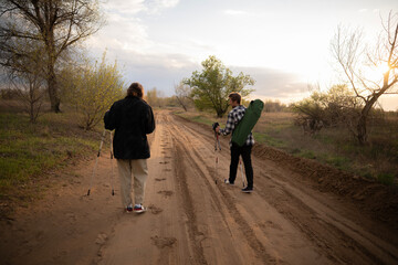Obraz premium Friends hike together along a sandy path, enjoying nature and the warm glow of sunset on their adventure