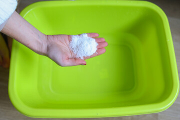 girl pours salt into hot water to steam her feet