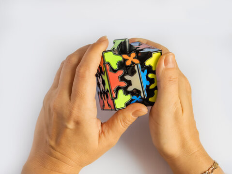 Braunschweig, Germany - December 10, 2024: women's hands and and type of Rubik's cube - Qiyi Crazy Gear Cube on a white background with copy space, Gear Puzzle, Raphael Puzzles, speedcubing
