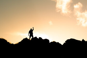 Man on top a mountain with fit up to the sky showing courage strength, People power, vision,...