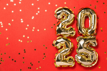 New year 2025 balloon celebration card. Gold foil helium balloon number 2025, party decoration, gold confetti stars on red background. Copy space, flat lay, merry christmas, happy holidays concept.