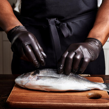 manos de un cocinero con guantes  pela y cocina un pescado en una cocina, beneficios omega 