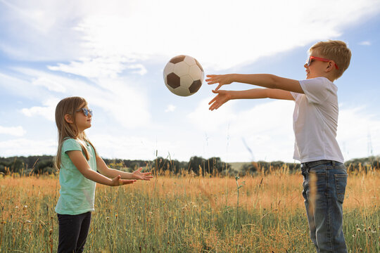 children playing in the park together throwing ball 