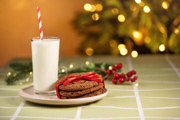 Close up traditional christmas milk glass with cookies on Christmas lights background. Festive food, Christmas celebration traditions. Milk for Santa Claus