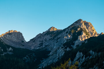Obraz premium Mountain peak Selenitza bathed in warm sunrise light seen from Loibl Pass in Karawanks, border Slovenia Austria. Wanderlust in Austrian Slovenian Alps. Tranquil atmosphere in alpine wilderness. Hike