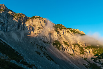 Mountain peak Begunjscica bathed in warm sunrise light seen from Loibl Pass in Karawanks, border Slovenia Austria. Wanderlust in Austrian Slovenian Alps. Tranquil atmosphere in alpine wilderness. Hike