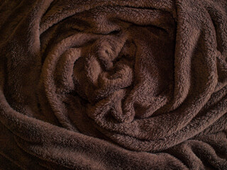 Cozy Fleece Blanket Rolled Up in Warm Brown Tones, Concept of Comfort, Relaxation, and Home Decor. Background, Texture