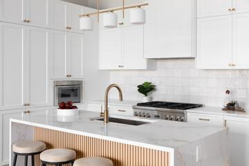 A kitchen detail with white cabinets and square tile backsplash, a waterfall marble countertop and...
