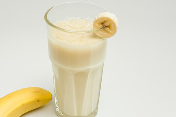 Glass of milk with bananas in it. Woman is drinking banana on gray background. Woman is drinking fruit milk from banana on gray background. A woman is drinking milk from a banana and a lifestyle.