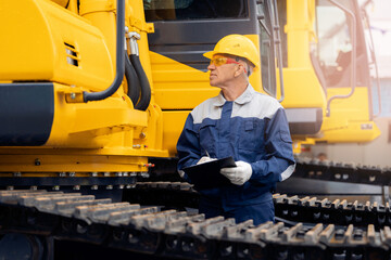 Worker with tablet inspects bulldozer at coal and sand quarry, concept industry truck maintenance