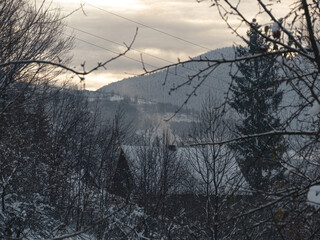 Smoke from the house's chimney. Winter in a village in the Transcarpathia region. Scenic snowy Carpathian mountains view