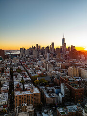 Aerial view of Lower Manhattan with one world trade center standing tall amidst the urban landscape, bathed in the warm glow of the setting sun