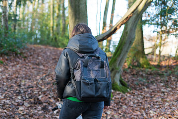 Back view of a woman with a backpack in the middle of a forest