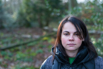 Young woman in autumn forest looking at camera with serious expression