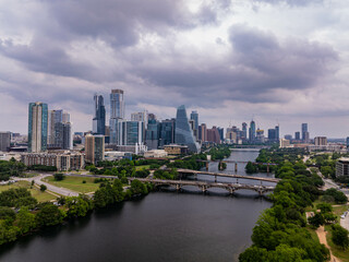 Aerial view of Austin skyline rising majestically above Colorado River, with a dramatic cloudy sky adding a touch of drama to the urban landscape