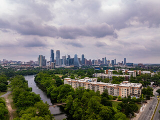 Austin, Texas skyline peeking through lush greenery and river, capturing the city's harmonious blend of urban and natural elements from above