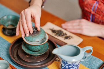 Green tea powder in ceramic bowl with bamboo whisk and wooden spoon on bamboo mat, evoking...
