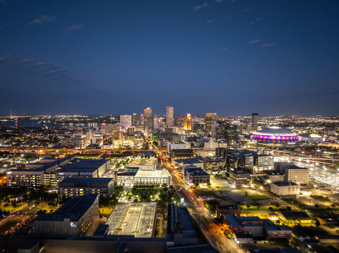 Glowing New Orleans city skyline at dusk with illuminated buildings, busy streets, and the Caesars Superdome, creating a captivating urban night view