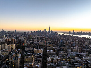 Glowing sunset hues light up the cityscape of Manhattan New York City, showcasing the iconic one world trade center in the background and Flatiron District in the foreground