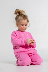 Portrait of cheerful playing girl. Child with smiles and funny emotions on light background. Vertical photo.