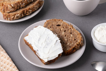 Slices of whole grain bread topped with cream cheese on a plate in a cozy kitchen setting