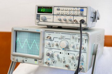 Green sine waves on the screen of a multi-button oscilloscope
