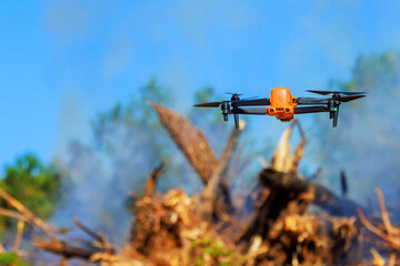 Using drone, an inspector monitors burning of uprooted trees during land clearing for construction
