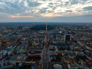 Berlin cityscape at dusk, aerial view of illuminated streets with traffic, Tiergarten Park, Alexanderplatz against a cloudy sky