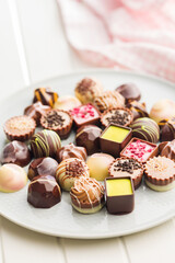 Mix of chocolate pralines on plate on white table.