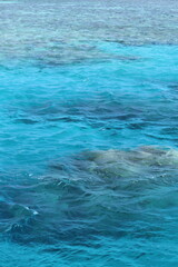 Turquoise waters of the Red Sea near Hurghada, Egypt, with visible coral reef formations and gentle waves on the surface, creating a serene and tropical seascape.