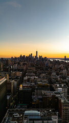Golden hour glow, New York City skyline illuminated during sunset, featuring One World Trade Center prominently and Financial District of Lower East Side, Manhattan