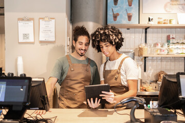 Cafe workers discussing orders with digital tablet device