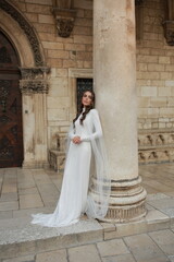 Obraz premium beautiful bride dressed in a white dress stands in the middle of the old town. wedding photoshoot in the old town of Croatia. old medieval castle