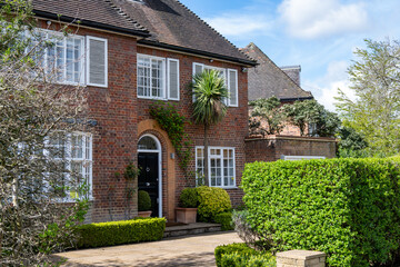 Walking on streets of North London, red brick houses and flowering gardens in spring, city life, wealthy neighbourhoods in London, UK