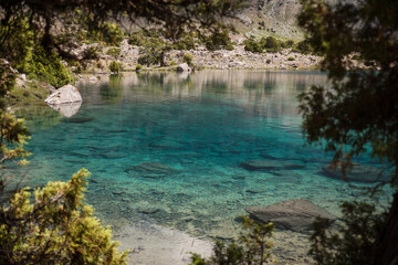 view of a blue mountain lake with clear water in which the bottom is visible