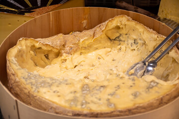 Italian food, buttery or firm blue cheese made from cow milk in Gorgonzola, Milan, Italy in large wooden box on Italian farmers market