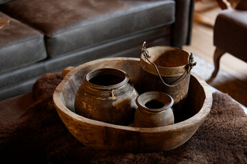 Aged pottery and wooden bowl on a fur rug.  Rustic, vintage decor.